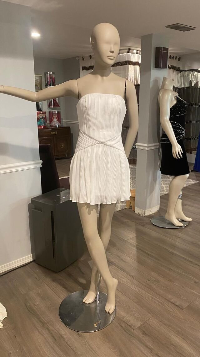 White pleated cocktail dress and black beaded velvet dress on mannequins in the boutique